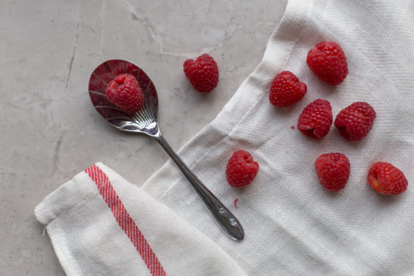 Raspberries on tea towel with spoon