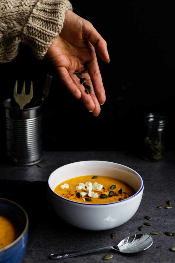 Sprinkling pumpkin seeds on butternut squash soup
