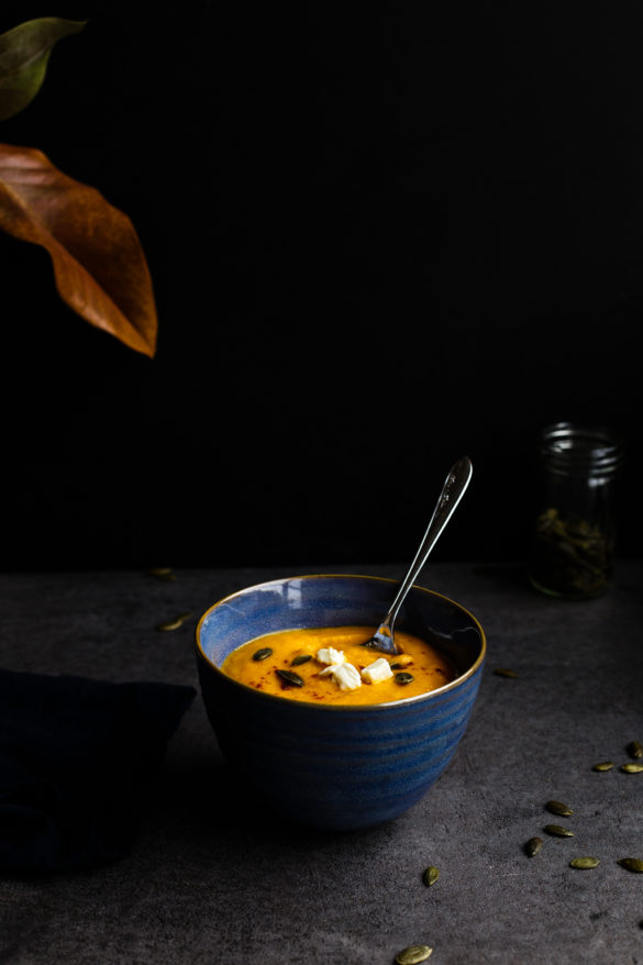 Butternut squash soup in blue bowl on black background